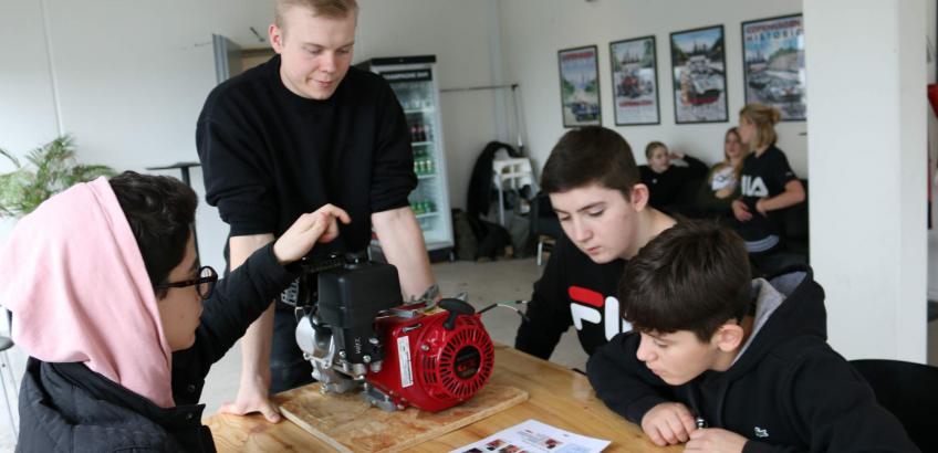 Underviser i racerløb viser eleverne en motor i Åben Skole forløbet